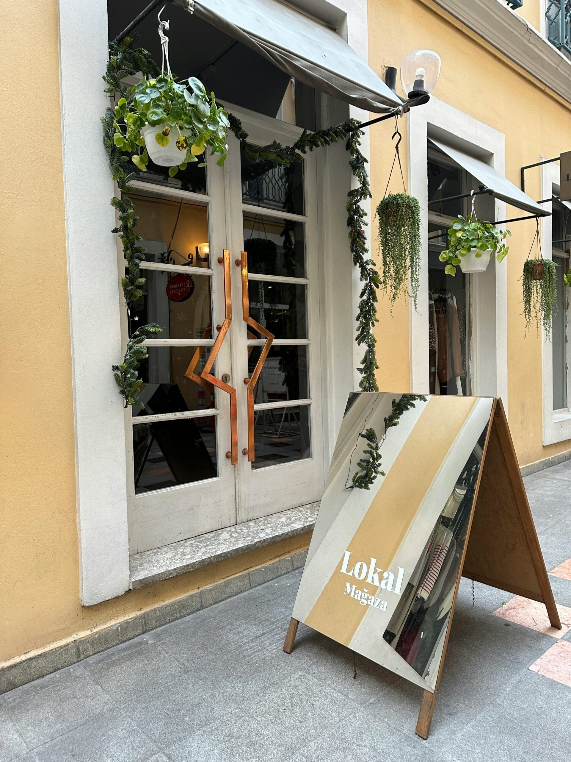 Stylish storefront with hanging plants and a prominent sign enhances urban charm.