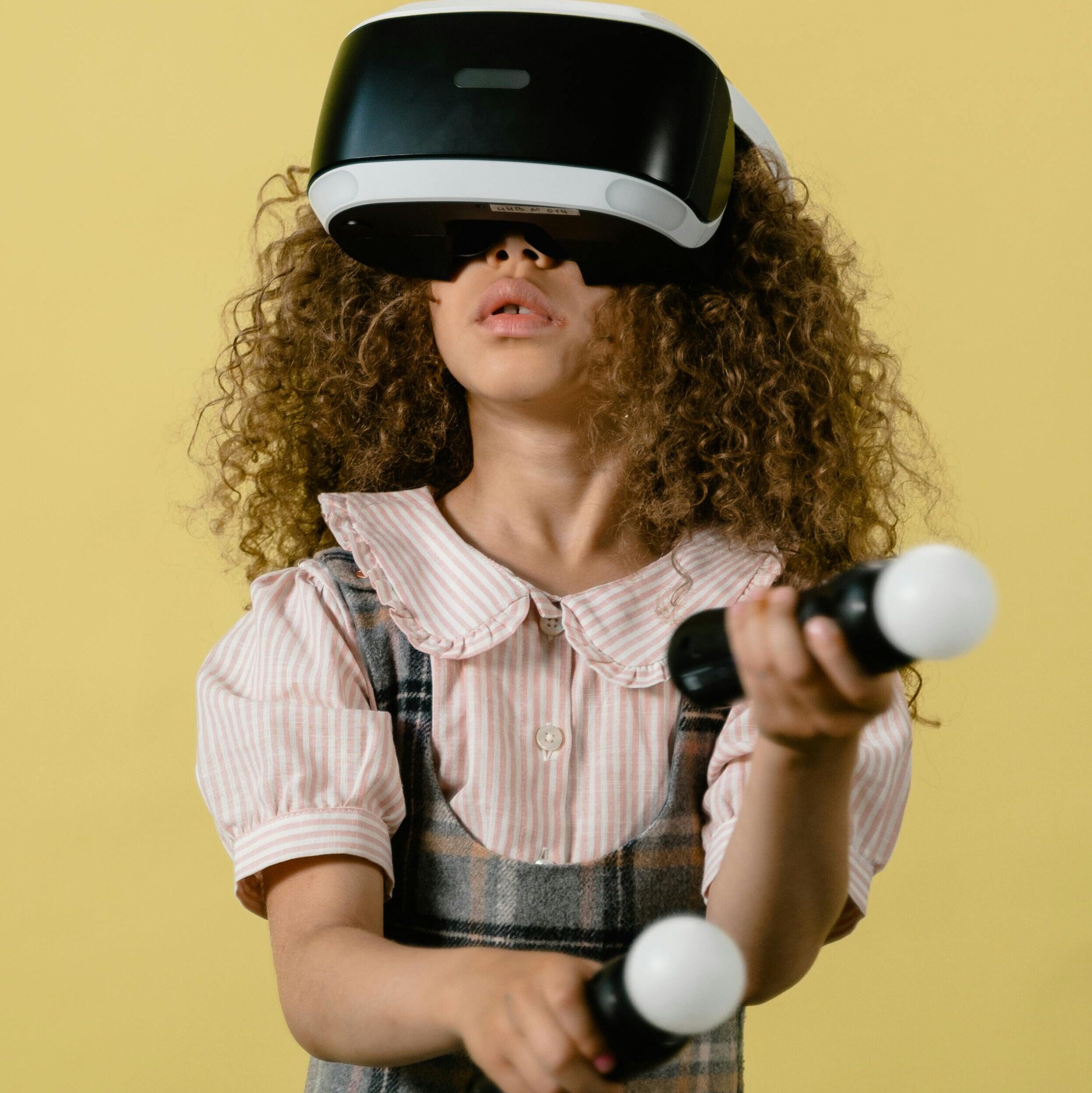 Curly-haired girl wearing VR headset and controllers, exploring virtual reality.